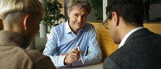 Innenaufnahme zeigt drei Kolleg*innen der GESOBAU im Gespräch im Foyer des Hauptsitzes.