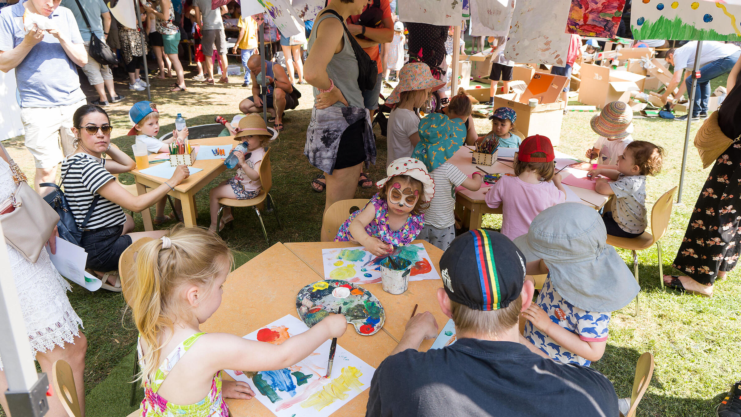 Außenaufnahme zeigt Kinder beim Malen.