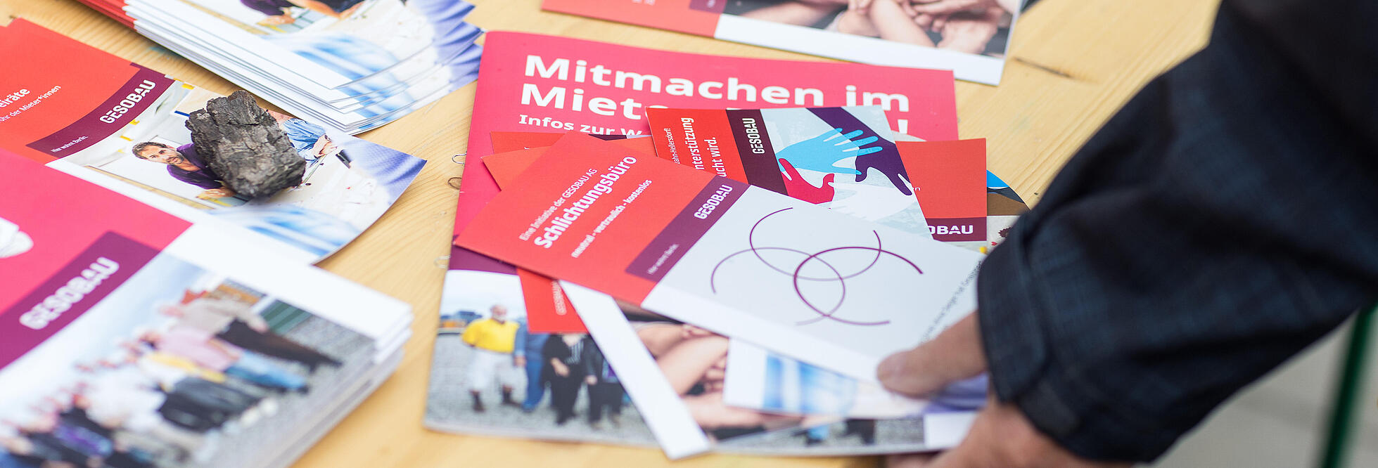 Außenaufnahme zeigt ein Detail von Informationsmaterialien zur Mieterratswahl 2022 bei der GESOBAU: Diverse Flyer liegen auf einer Bank.