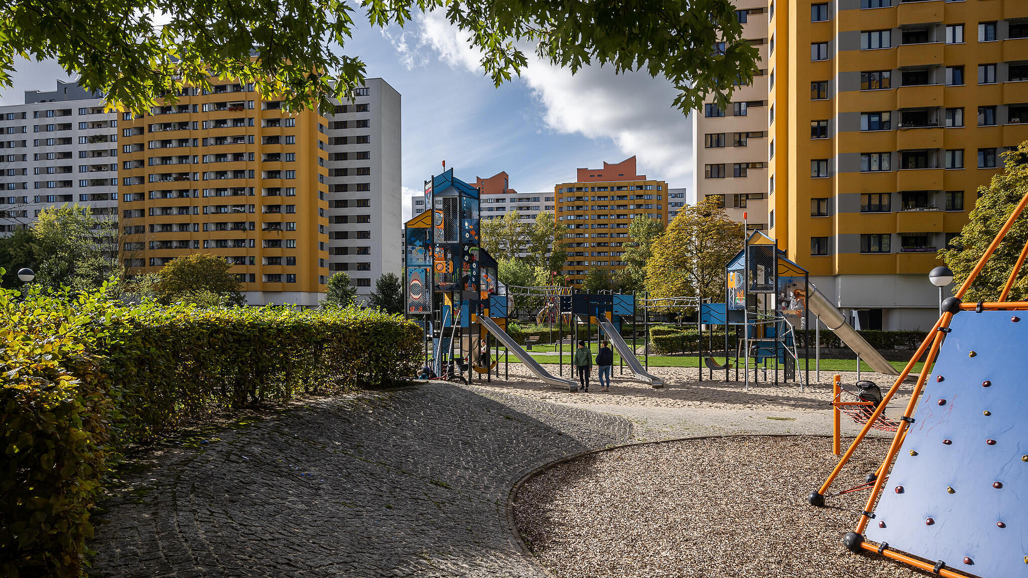 Bild zeigt neugestaltete Grünanlagen im Märkischen Viertel, mittig Spielplatz zum Klettern und rutschen. Im Hintergrund Wohnhäuser.