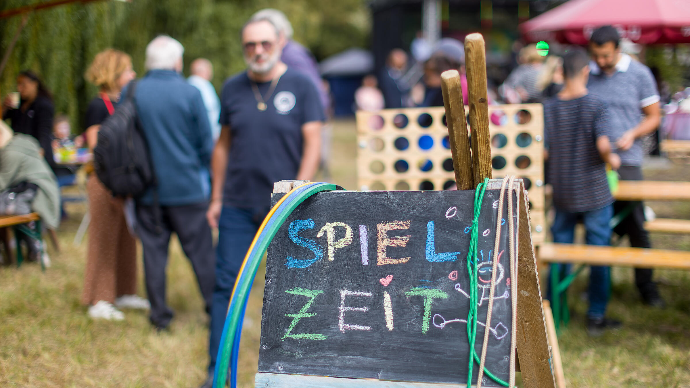 Außenaufnahme zeigt eine aufgestellte Tafel, auf der mit bunter Kreide "Spielzeit" geschrieben steht. 