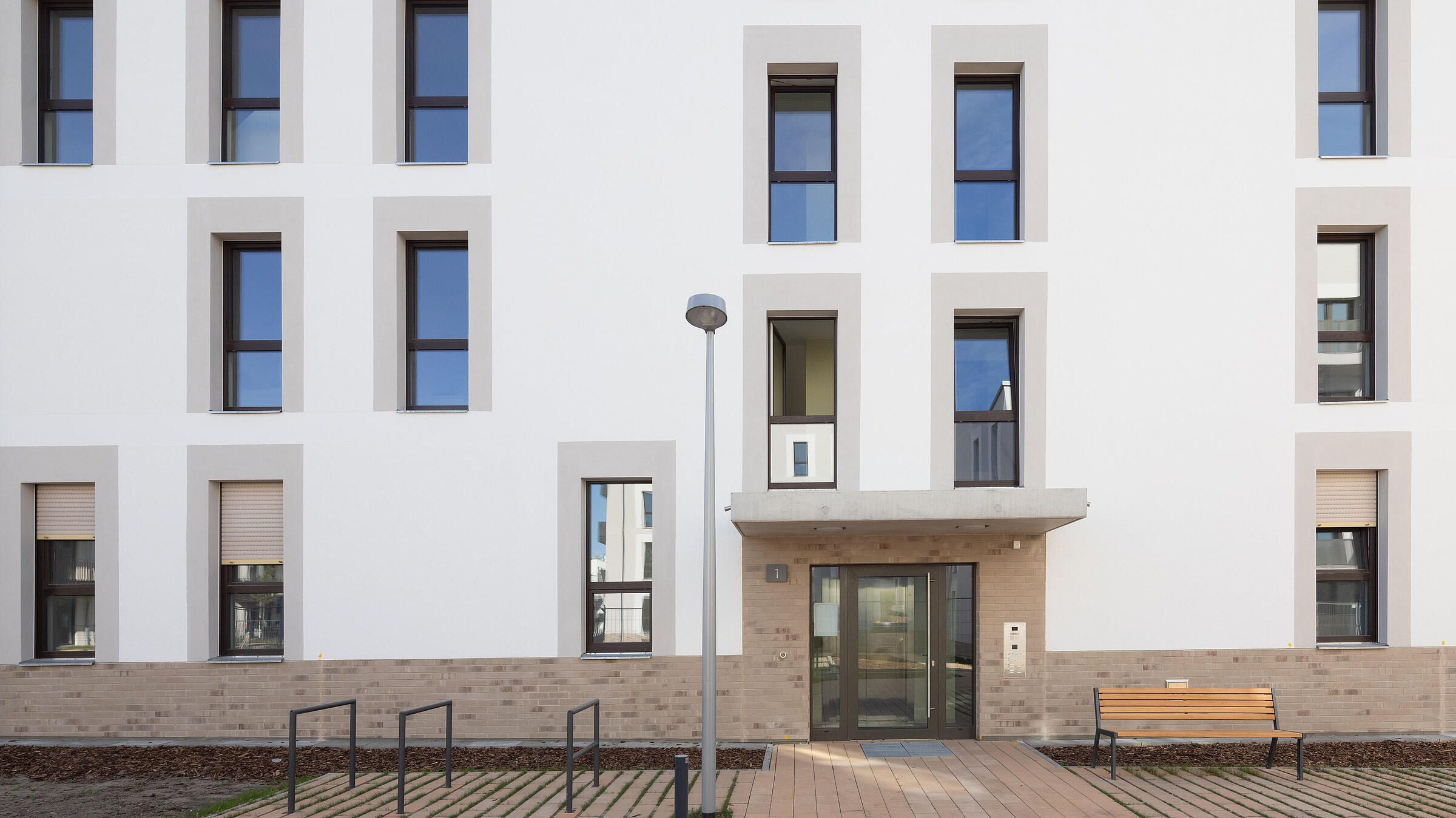 Bild zeigt fertiggestellten Eingangsbereich und Fassade eines neuen Wohnhauses an der Beate-Hahn-Straße/Marianne-Förster-Straße.
