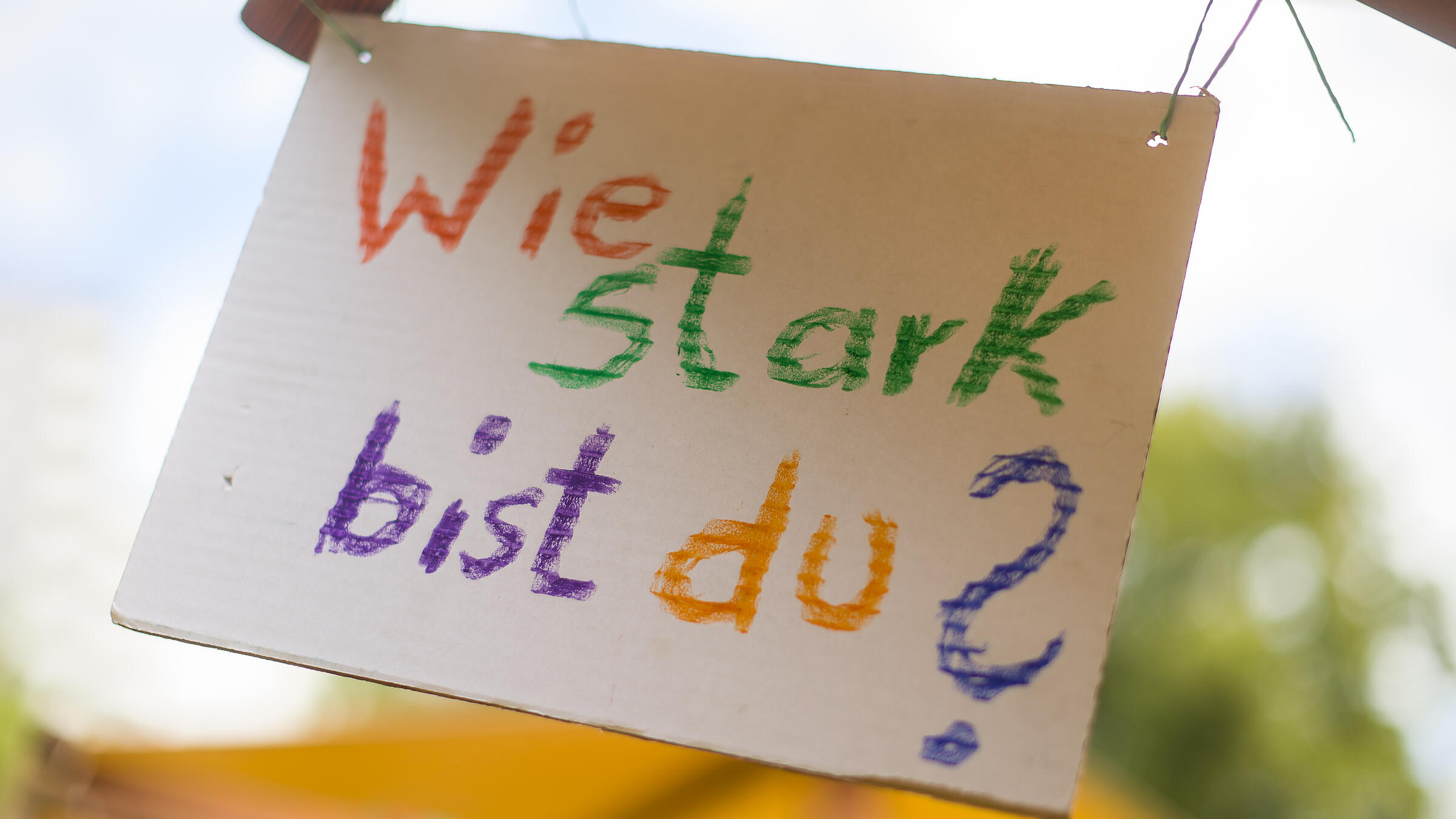 Außenaufnahme zeigt ein buntes, handbeschriebenes Schild mit der Aufschrift "Wie stark bist du?"