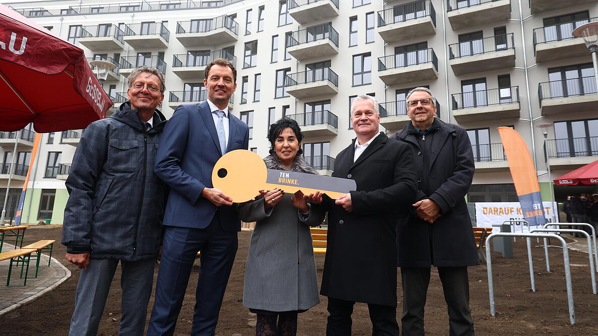 Bild zeigt Schlüsselübergabe in der Titiseestraße am 6. November 2024 (v.l.n.r.): Christian Gaebler (Senator Stadtentwicklung, Bauen und Wohnen), Arjen ten Brinke (Geschäftsführer Ten Brinke), Emine Demirbüken-Wegner (Bezirksbürgermeisterin Reinickendorf), Christian Wilkens (Vorstand GESOBAU) und Thomas Harms (Superintendent Kirchenkreis Reinickendorf). In der Mitte großer Schlüssel. Im Hintergrund Wohngebäude.