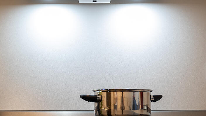Topf steht auf einer Kochfläche, darüber hängt ein Sensor, der bei möglicher Gefahr Alarm schlägt.
