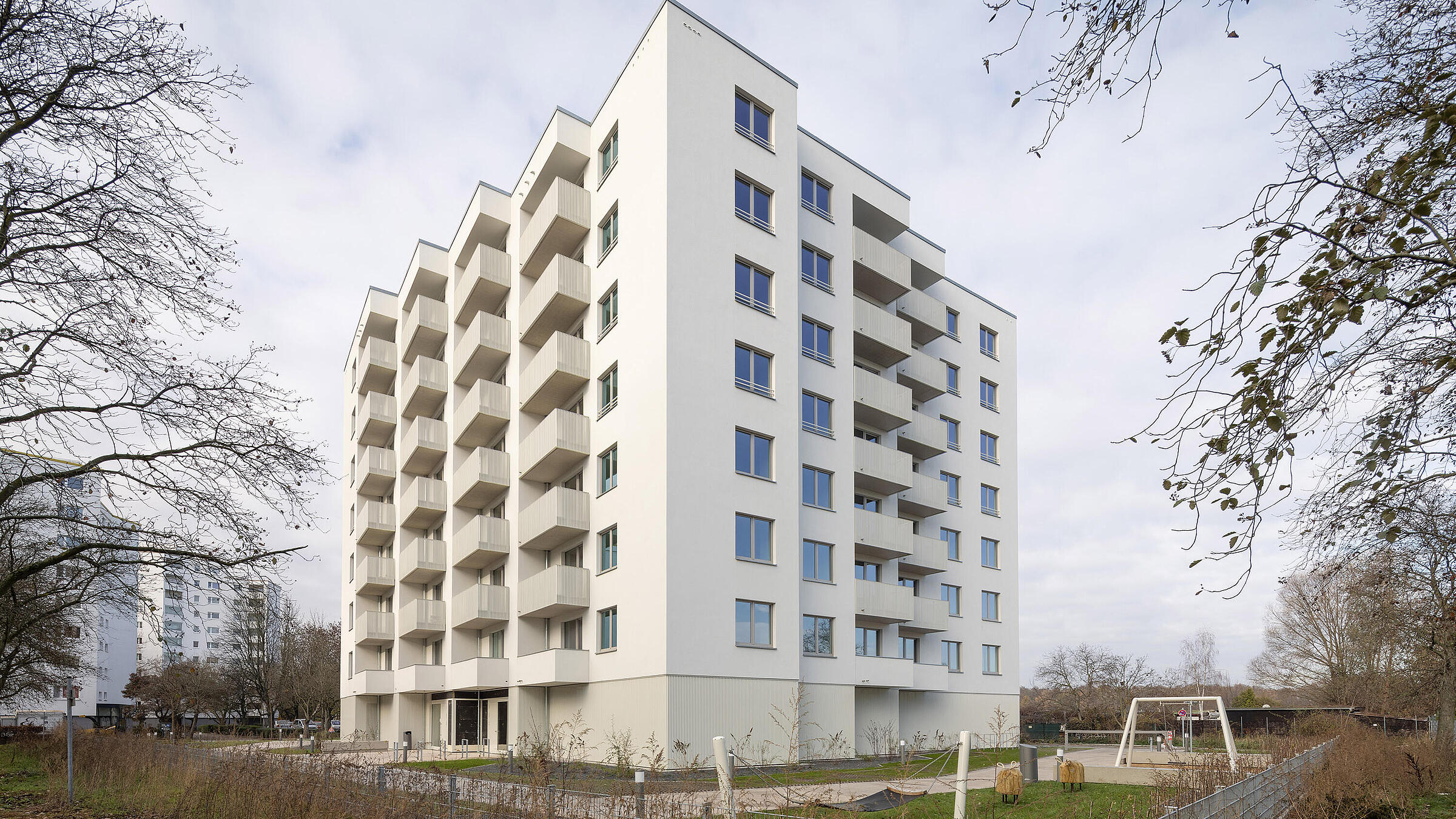 Bild zeigt Außenansicht Neubau in der Finsterwalder Straße, im Vordergrund Grünflächen und Spielbereich.