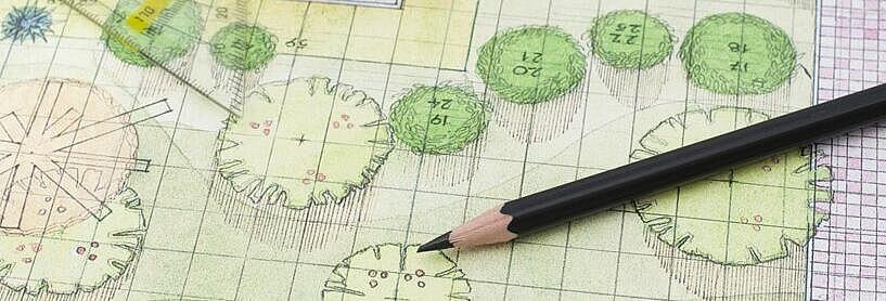 Nahaufnahme einer architektonischen Zeichnung einer Grünfläche, auf der ein Geodreieck und mehrere Stifte liegen