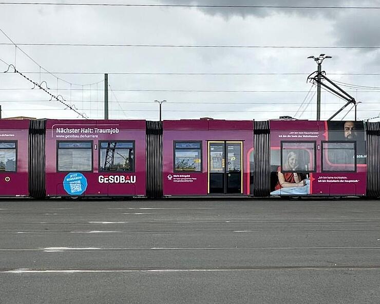 Außenaufnahme zeigt eine Berliner Straßenbahn mit Beklebung im GESOBAU-Design zur Gewinnung von neuen Mitarbeitenden.