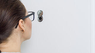 Frau schaut durchs Schlüsselloch