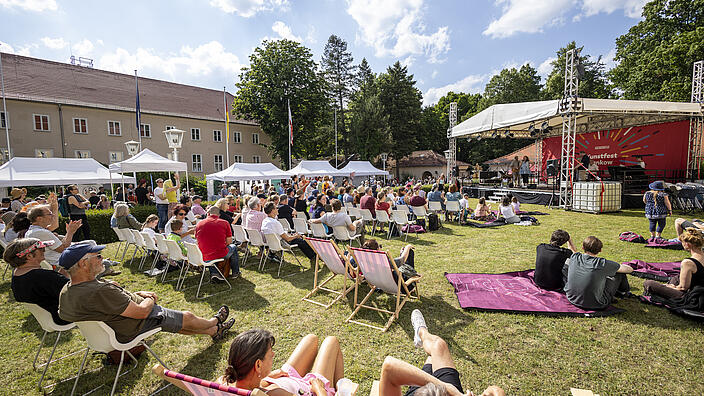 Kunstfest-Besucher auf einer Wiese vor der Bühne