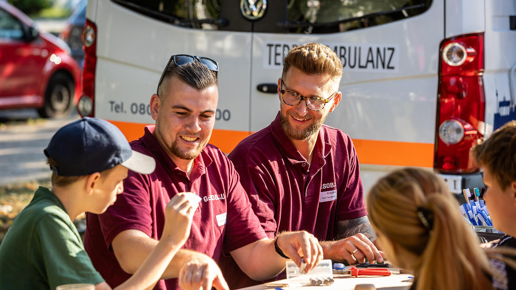 Außenaufnahme zeigt zwei Mitarbeiter der GESOBAU AG im Gespräch mit Kindern.