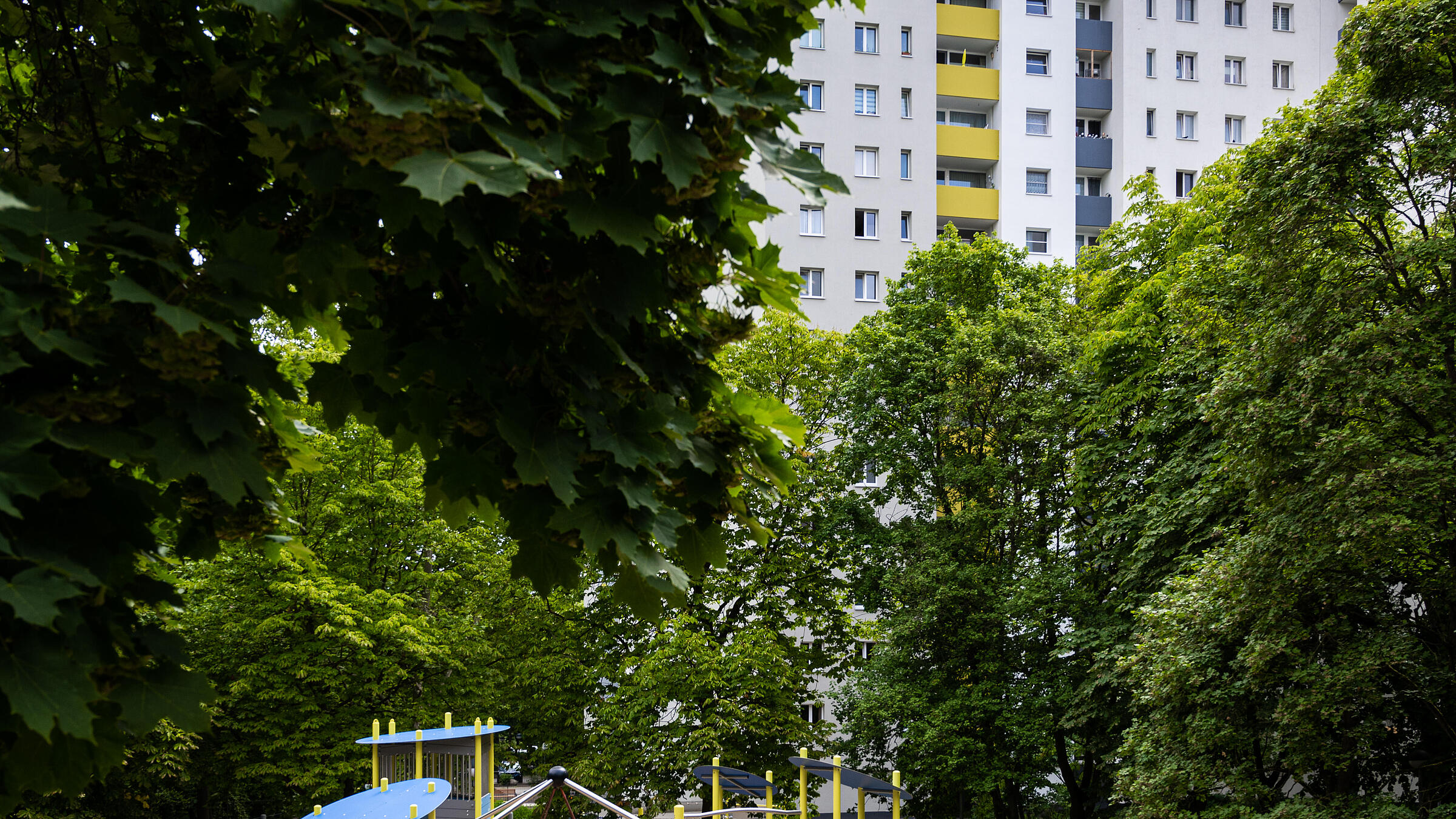 Außenaufnahme zeigt neuen Spielplatz am Eichhorster Weg, umgeben von Bäumen und Grünflächen. Im Hintergrund Wohnhaus.
