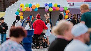 Menschen schauen sich dekorierte Marktstände mit Infomaterial an