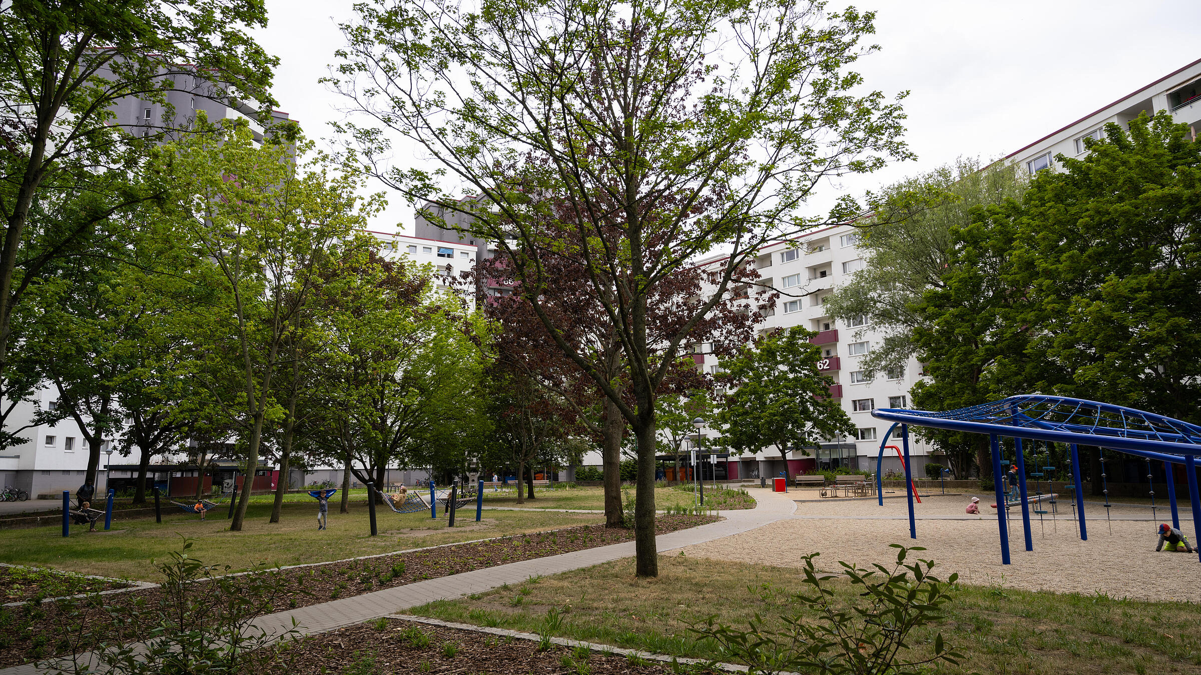 Außenaufnahme Gesamtüberblick neuer Spielbereich zwischen Senftenberger Ring und Finsterwalder Straße, umgeben von Grünflächen. Im Hintergrund Wohnhäuser.