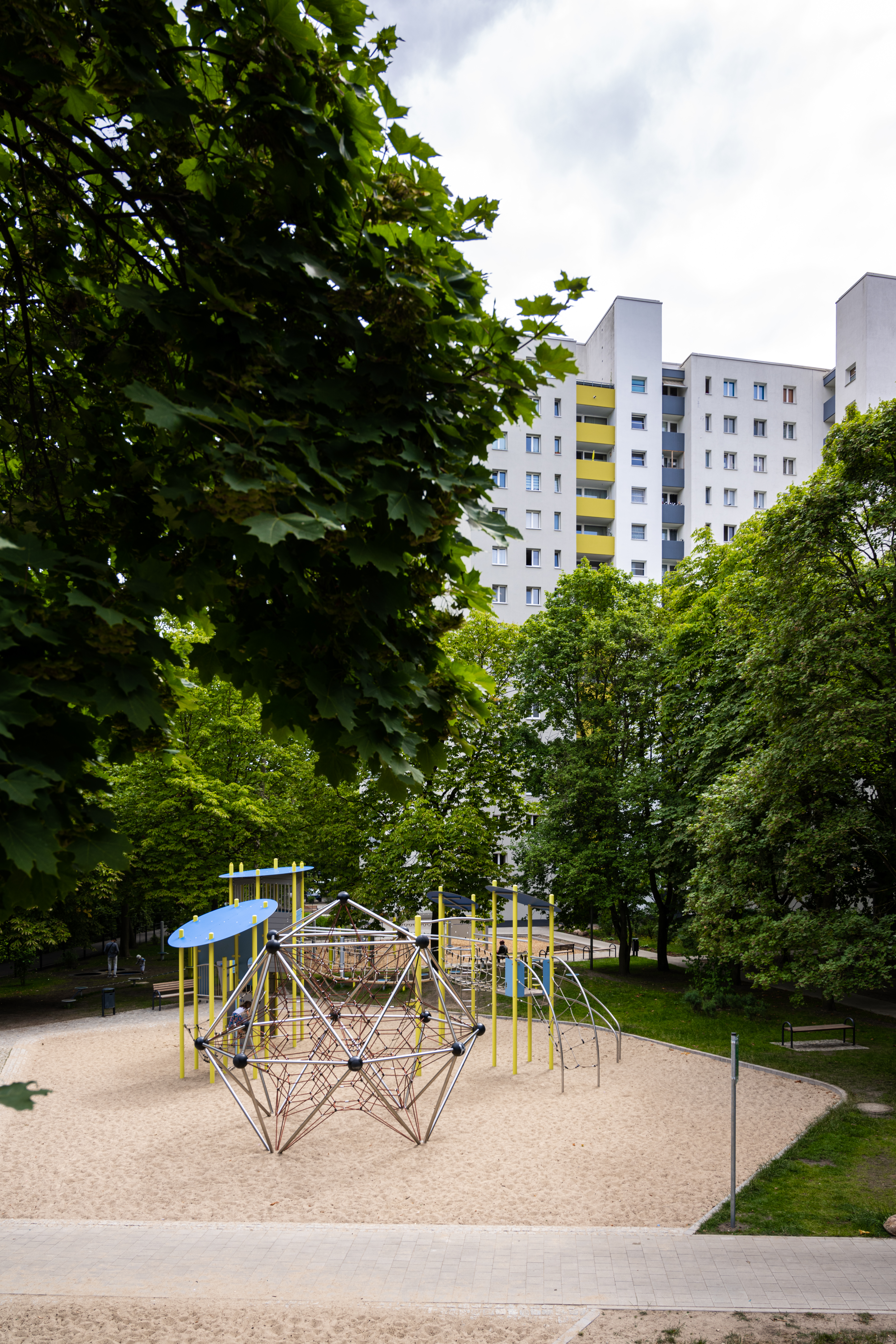 Außenaufnahme zeigt neuen Spielplatz am Eichhorster Weg, umgeben von Bäumen und Grünflächen. Im Hintergrund Wohnhaus.