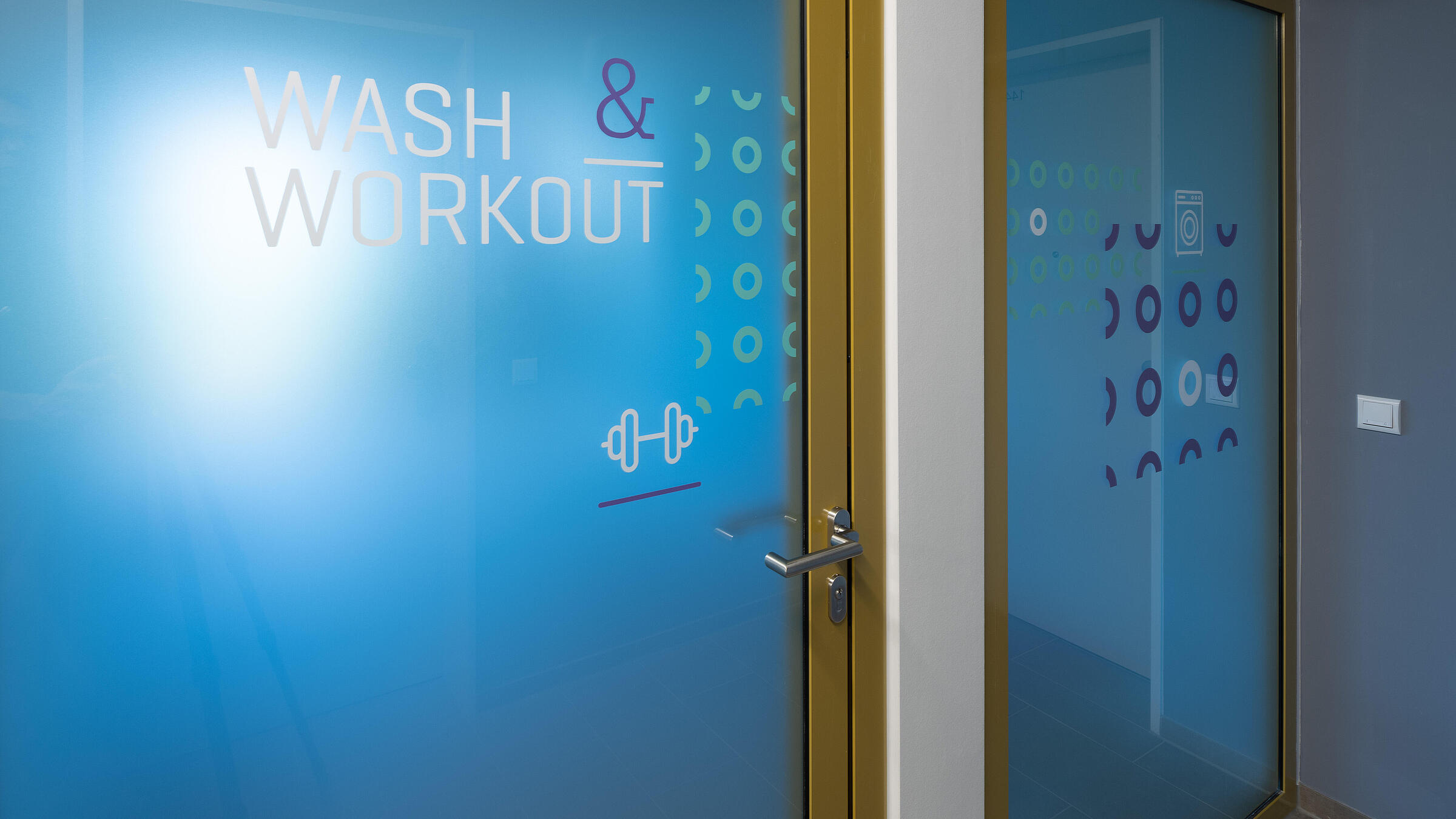 Innenaufnahme zeigt die Tür zur Gemeinschaftsfläche "Wash & Workout".